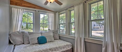 A bedroom with a bed, a ceiling fan, and multiple windows.