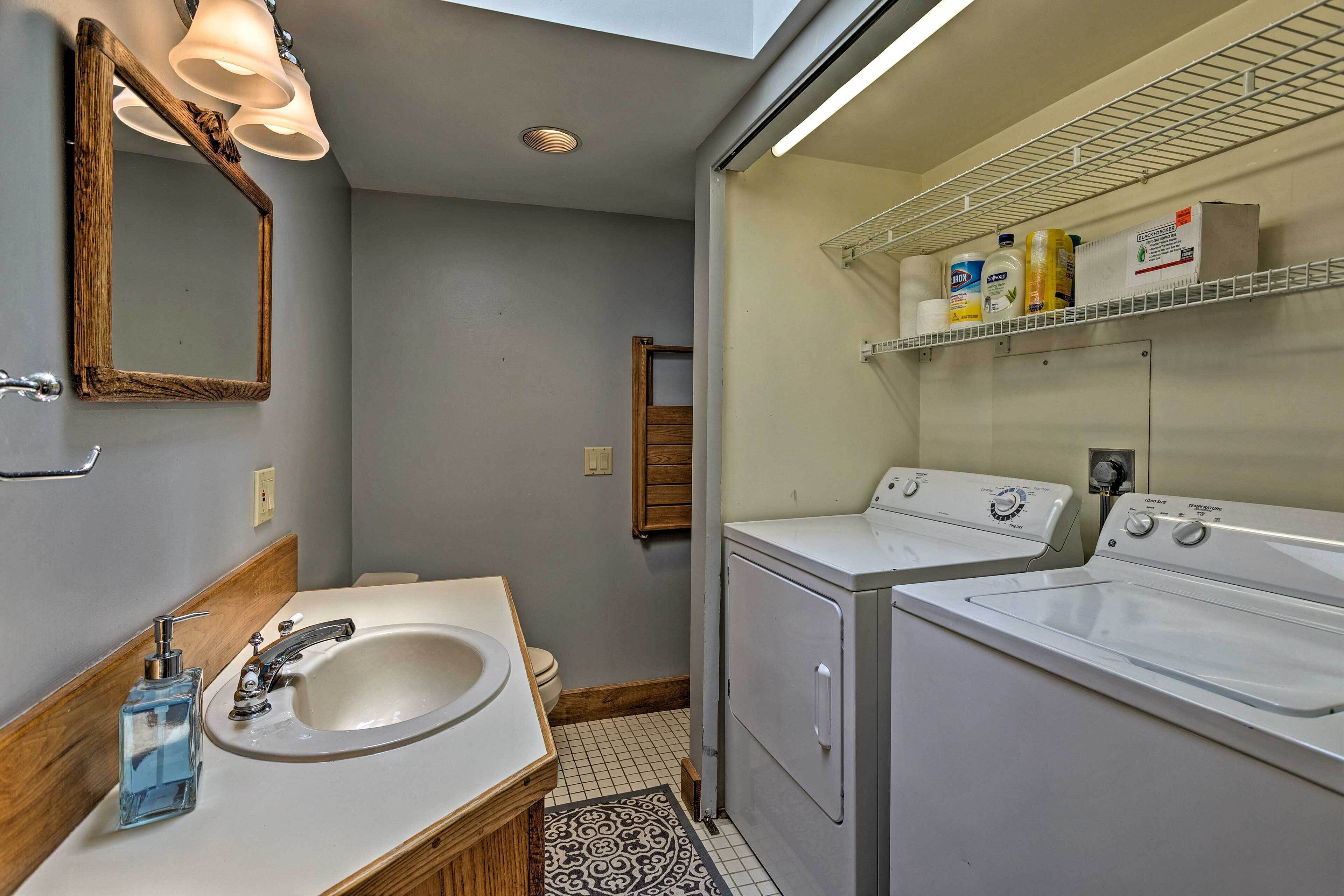 A bathroom with a sink, mirror, and two washing machines.