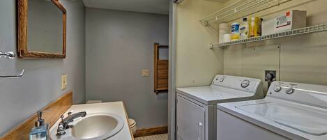 A bathroom with a sink, mirror, and two washing machines.