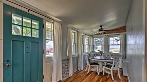 A room with a teal door, wooden flooring, a dining table with chairs, and a ceiling fan. - Common Fence Point Cottage w/ Ocean Views! (Portsmouth)