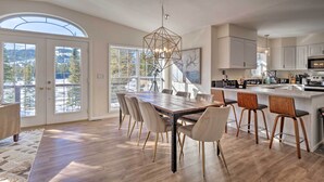 Une cuisine spacieuse dotée d’un grand îlot central, de meubles blancs et d’un coin repas avec une longue table et des chaises.