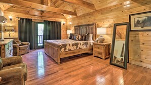 Ein Schlafzimmer in einer Blockhütte mit einem hölzernen Bett, zwei Nachttischen, einer Kommode und einem großen Spiegel.