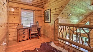 Ein Holzblock-Innenraum mit Schreibtisch, Stuhl und einem großen Fenster mit Jalousien.