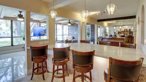 Une cuisine spacieuse dotée d’un grand îlot central, de tabourets de bar et de luminaires suspendus.