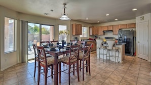 A spacious kitchen with wooden cabinets, a central island with bar stools, and a large dining table with chairs. - Private Pool & Hot Tub: San Tan Valley Home (San Tan Valley)