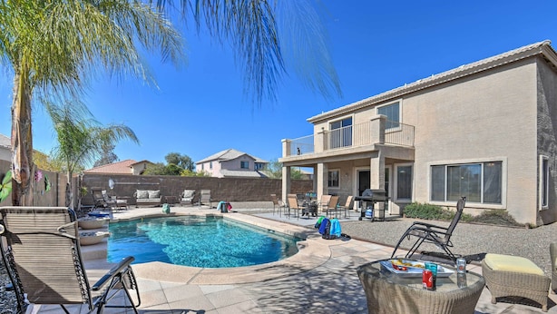 A swimming pool with lounge chairs and a table, surrounded by a house and palm trees. - Private Pool & Hot Tub: San Tan Valley Home (San Tan Valley)