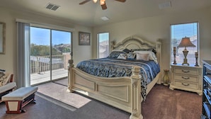A bedroom with a large bed, a ceiling fan, a dresser, a bench, and a view through the window. - Private Pool & Hot Tub: San Tan Valley Home (San Tan Valley)