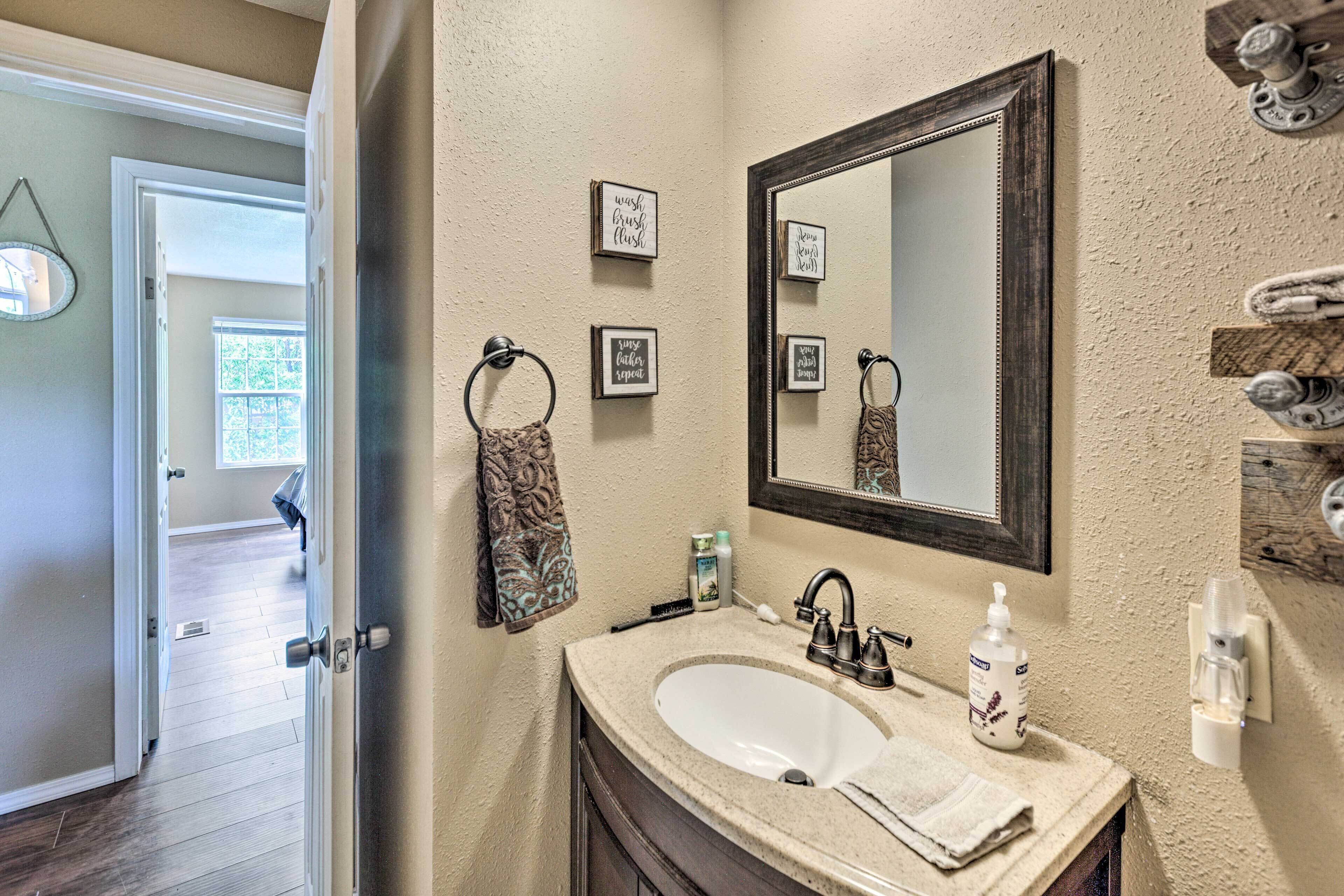 A bathroom with a sink, mirror, towel rack, and a door leading to another room.