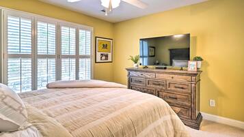 A bedroom with a bed, a dresser, a mirror, and a ceiling fan.