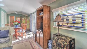 A room with a dining area, a wooden cabinet, a lamp, and a window with decorative glass panels.