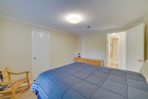 Une chambre à coucher avec un grand lit, deux portes, une commode en bois et une chaise.