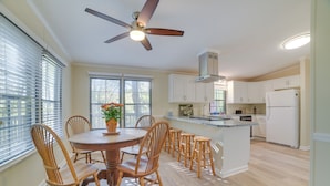 A spacious kitchen with a central island, wooden chairs, and a ceiling fan. - Stanardsville Cabin Rental ~ 24 Mi to Shenandoah! (Stanardsville)