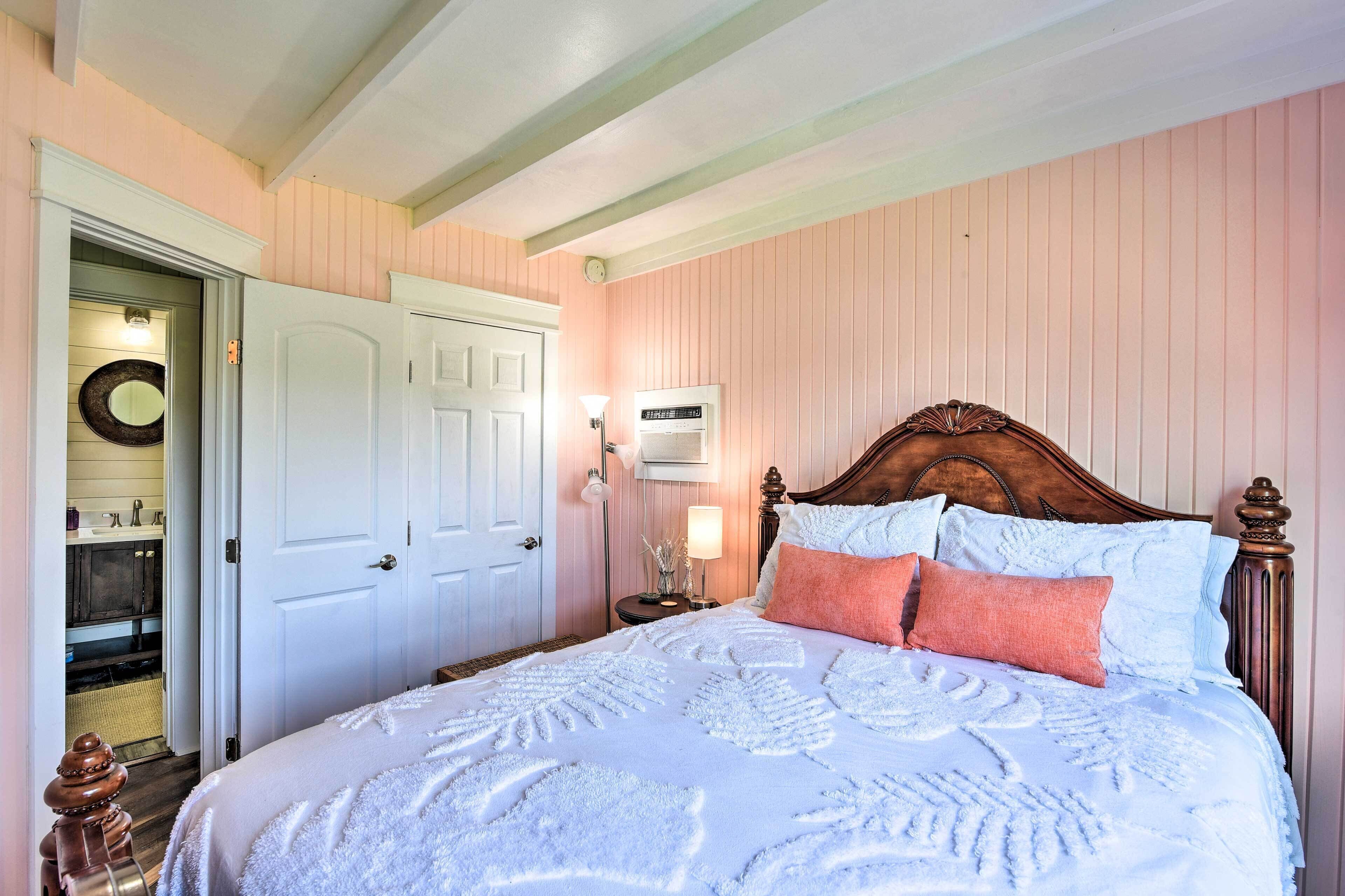 A neatly made bed with a patterned bedspread, a wooden headboard, and two bedside lamps.