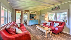 A spacious living room with a red leather sofa, a wooden coffee table, and a blue dresser. - Furnished Deck & Dock: Renovated Sargent Cabin! (Bay City)