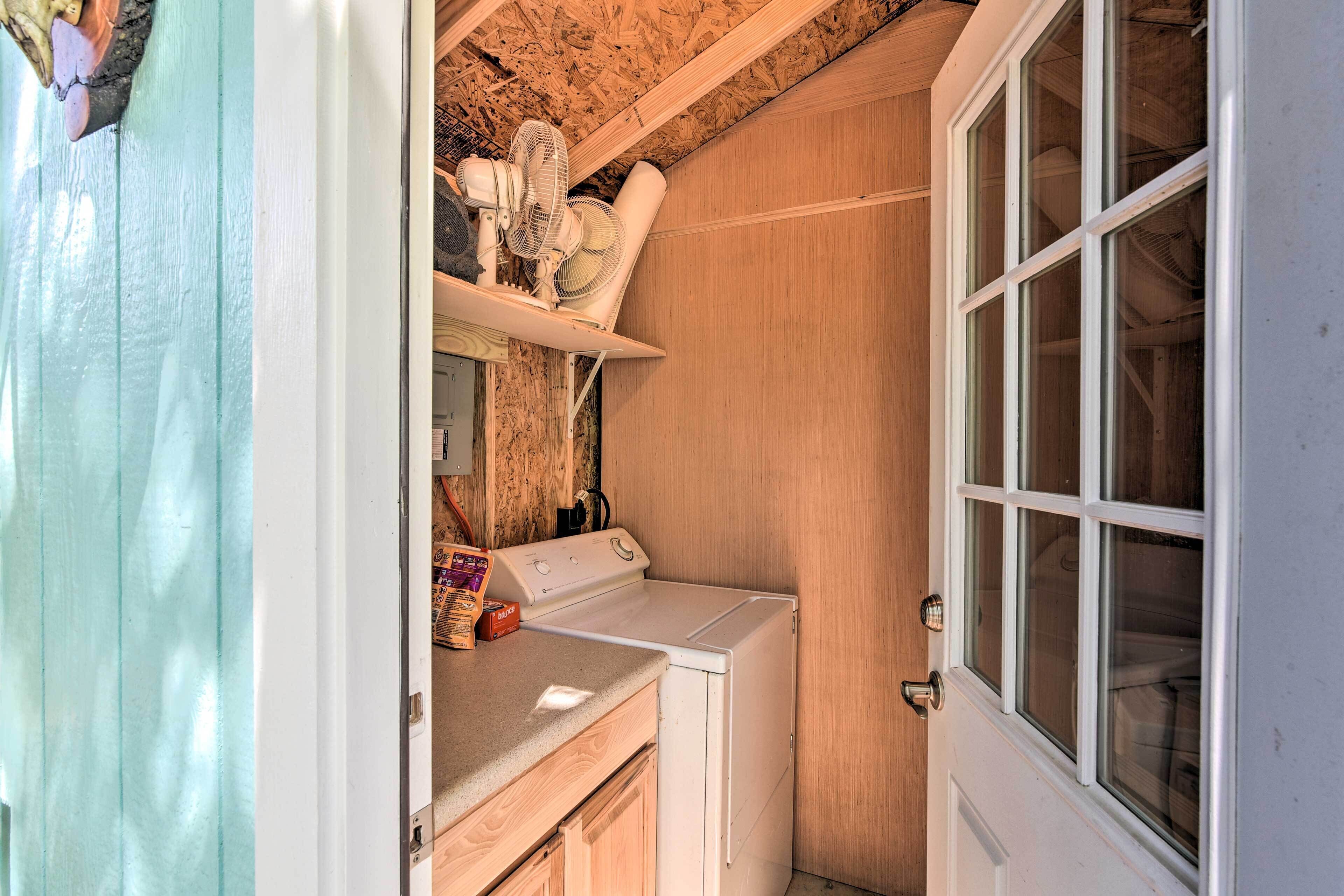 A laundry room with a washing machine, a fan, and a wooden door.