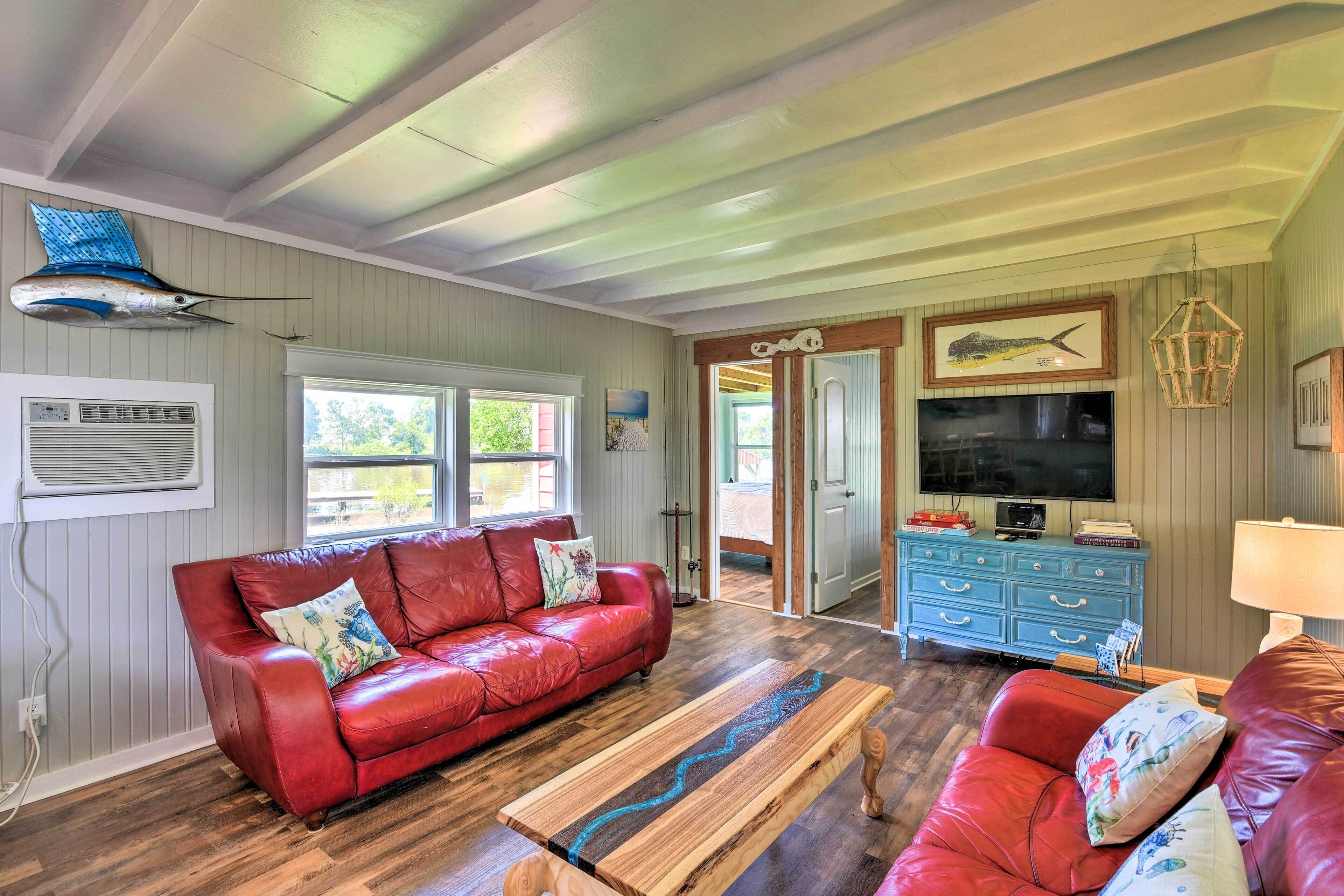 A living room with a red leather sofa, a wooden coffee table, a blue dresser, and a mounted fish sculpture.