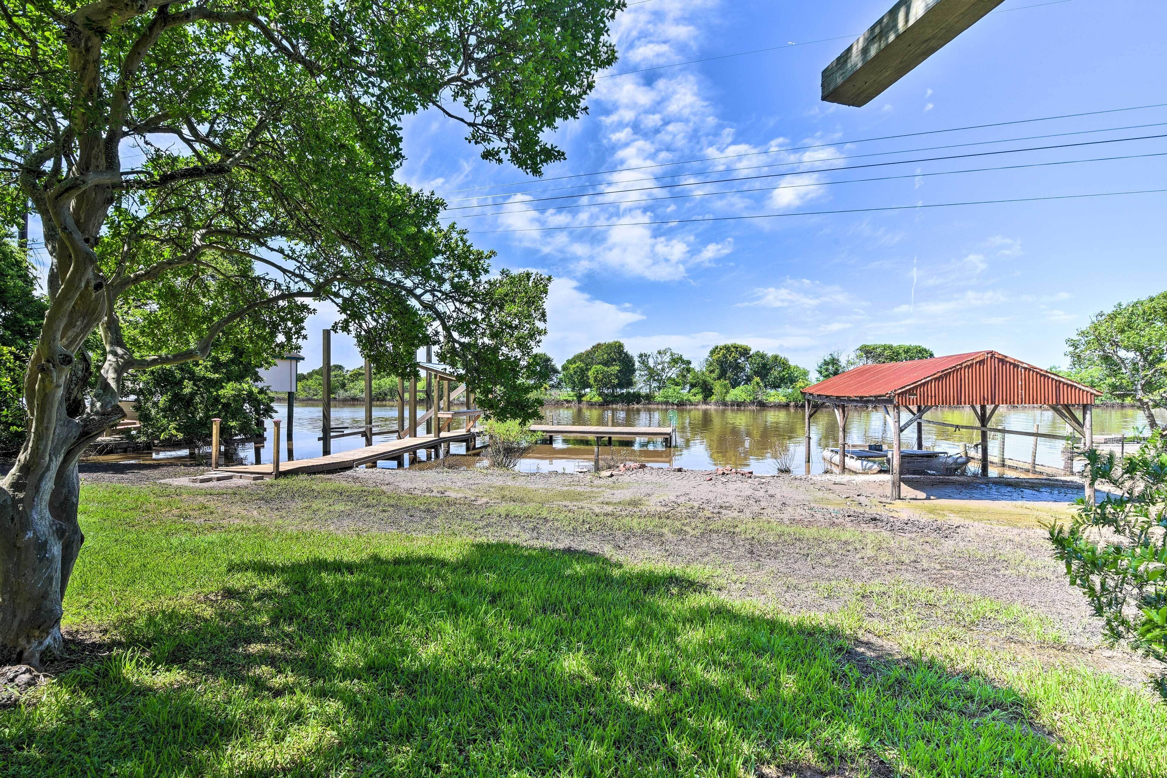 A lakeside park with a wooden deck, a covered pavilion, and a boat dock.