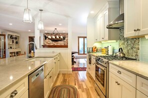 A modern kitchen with a central island, stainless steel appliances, and a brick accent wall. - Large Kennebunk Home, Walk to Beach < 2 Mi to Town (Kennebunk)