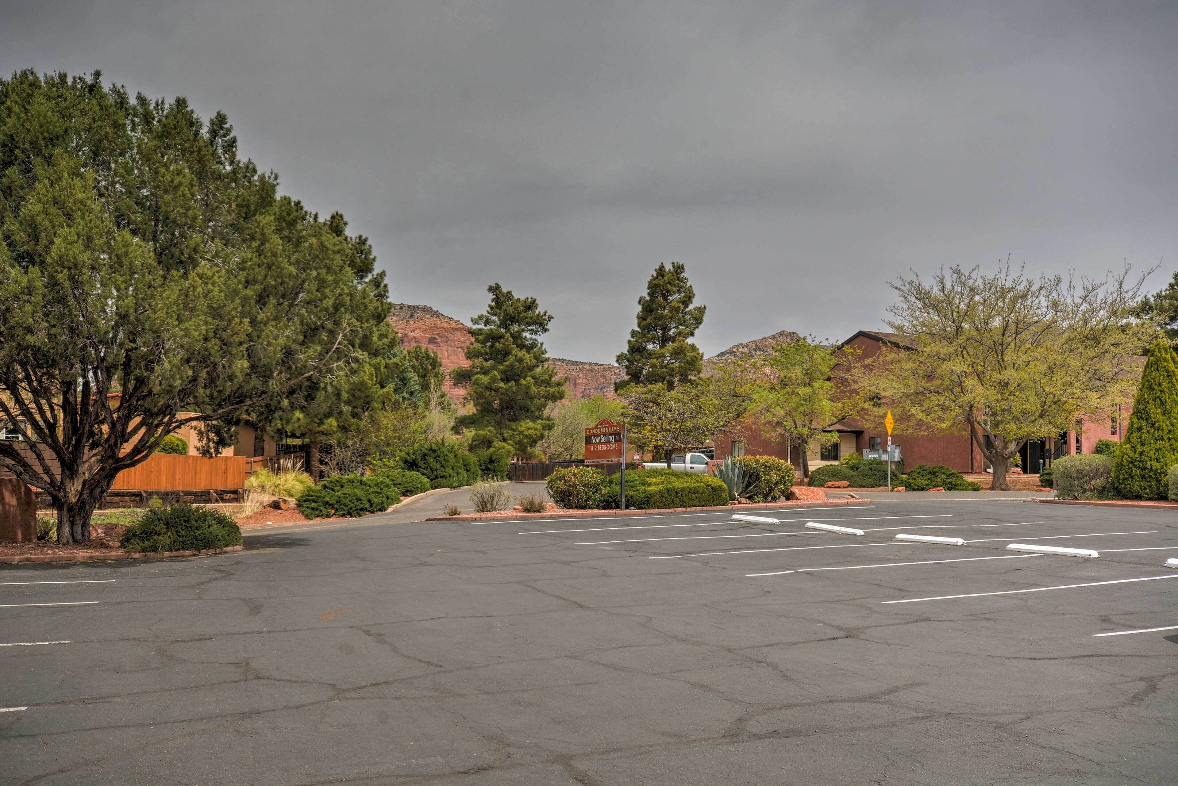 A parking lot with marked spaces, a sign for a hotel, and surrounding trees and buildings.