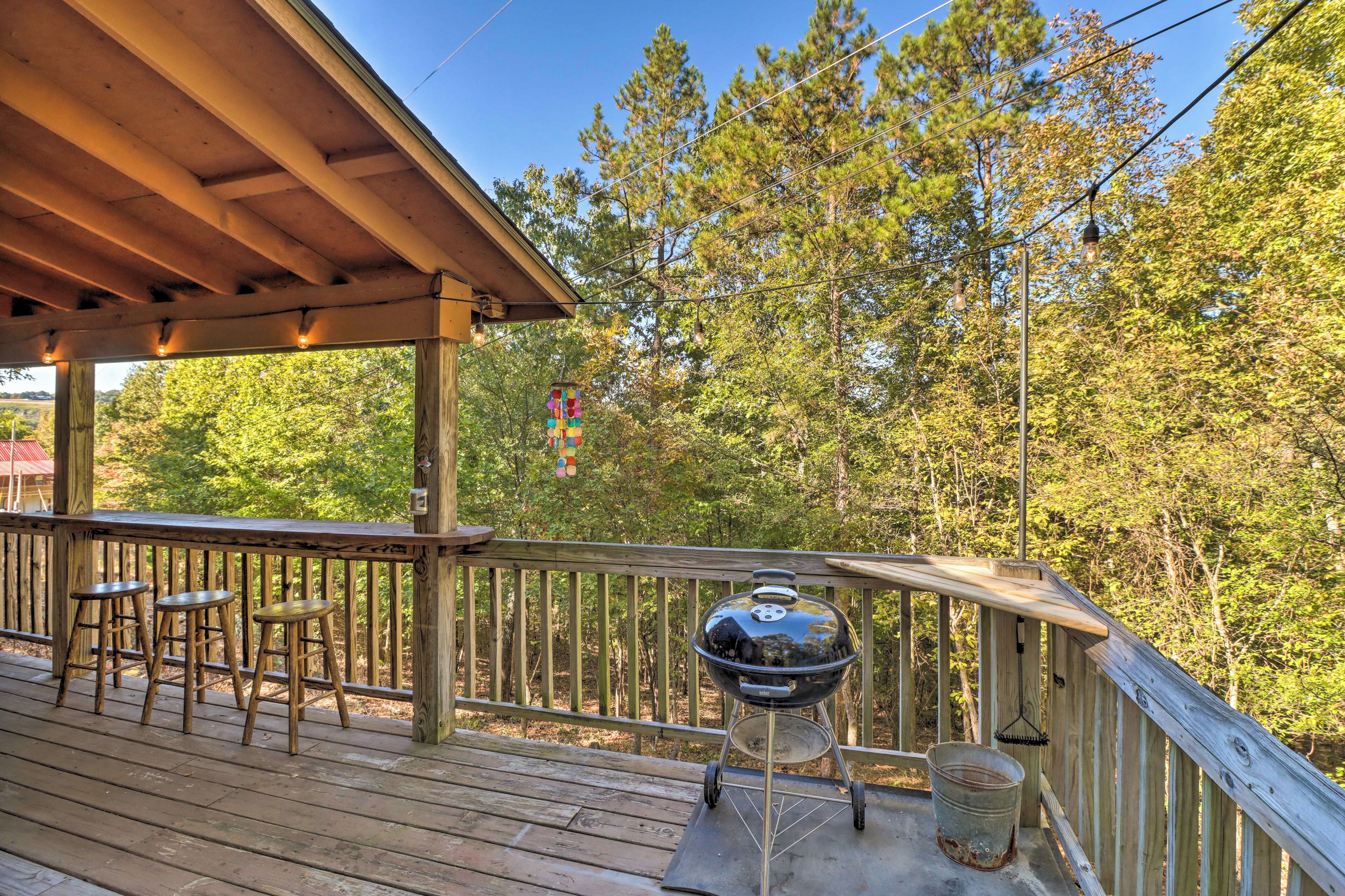 Une terrasse en bois avec un barbecue et des tabourets.