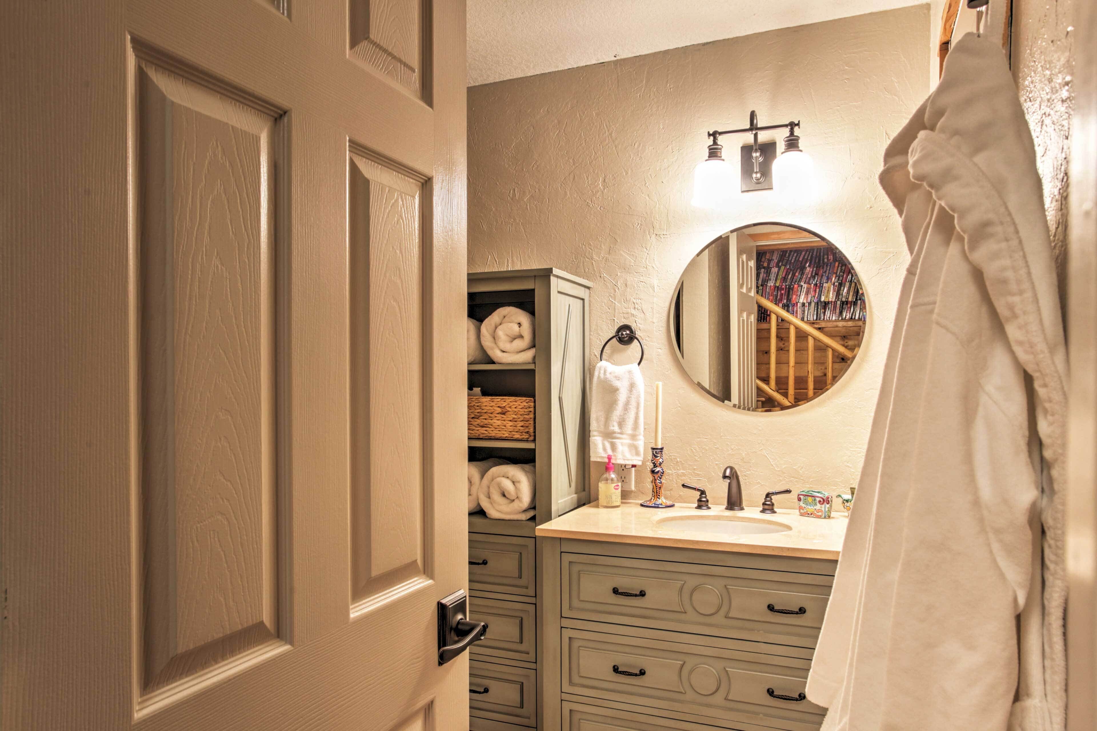 A bathroom with a beige door, a sink with a mirror above it, and a towel rack with a white towel.