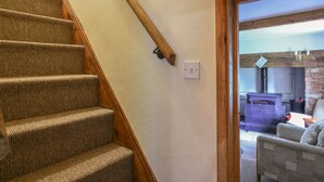 A staircase with a wooden handrail and carpeted steps leading to a doorway. - Millwater Cottage (Axminster)