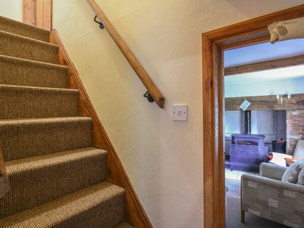 A staircase with a wooden handrail and carpeted steps leading to a doorway.