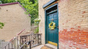A brick building with a green door, a metal railing, and a flower basket. - Charming Getaway < 1 Mi to Downtown Lambertville! (Lambertville)