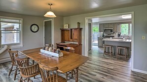 A spacious kitchen with wooden cabinetry, a dining table with chairs, and a visible clock on the wall. - Millersburg Home w/ Covered Porch & Fire Pit! (Millersburg)