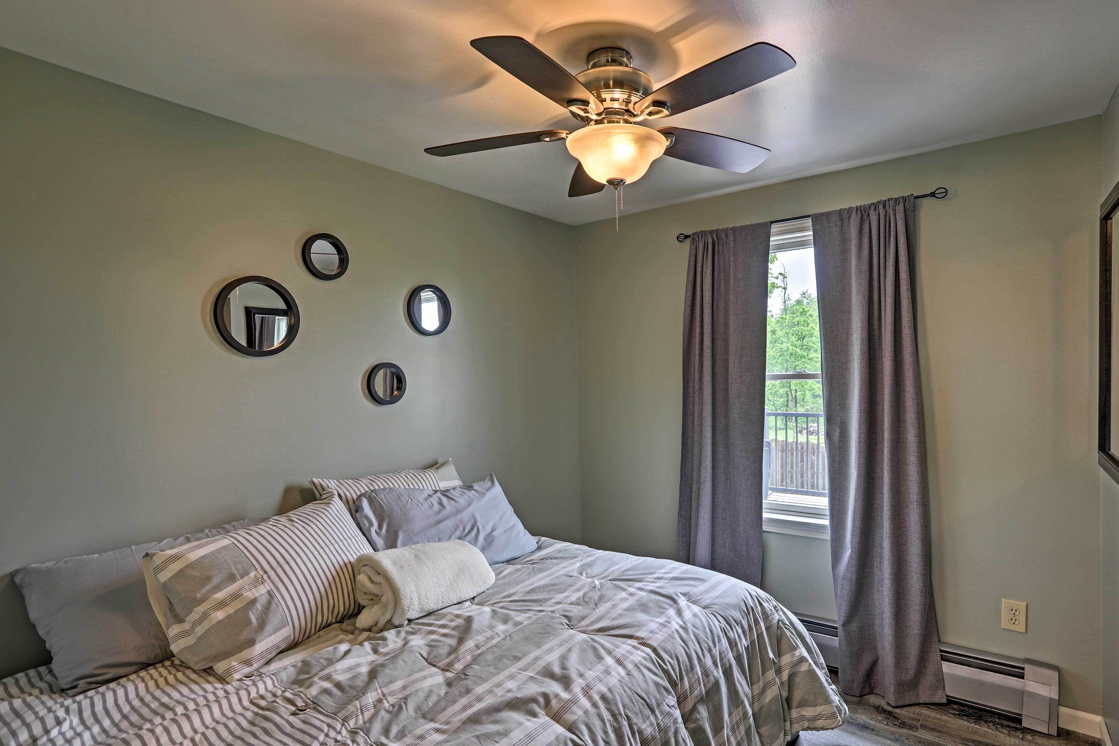 A bedroom with a bed, a ceiling fan, and a window with curtains.
