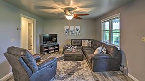 A living room with a ceiling fan, a sectional sofa, a coffee table, and a TV stand. - Millersburg Home w/ Covered Porch & Fire Pit! (Millersburg)