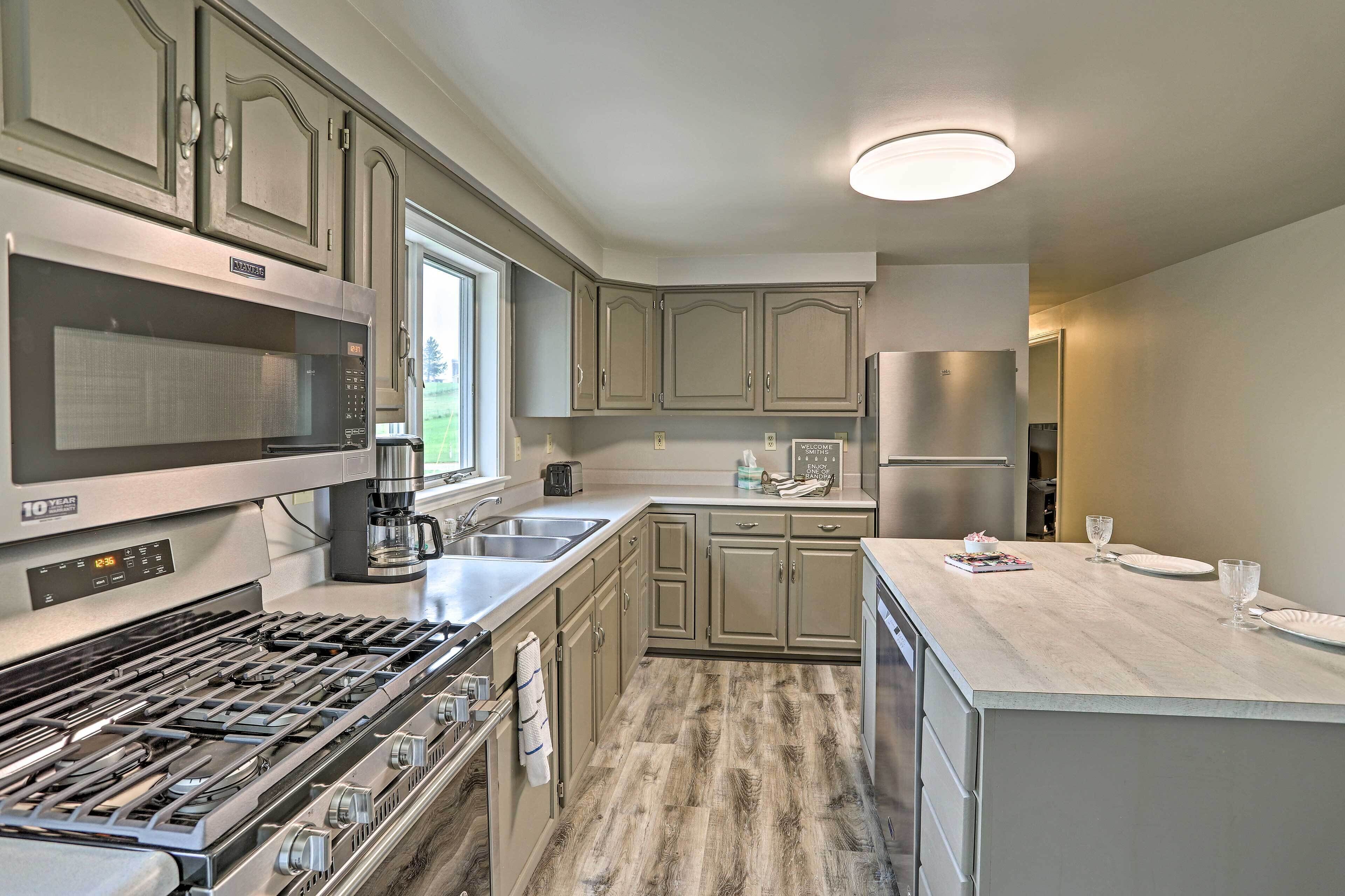 A modern kitchen with stainless steel appliances, a large island, and light wood flooring.