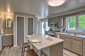 A modern kitchen with a central island, built-in appliances, and large windows.