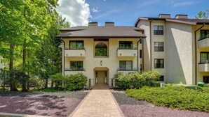 A multi-story building with a central entrance, surrounded by greenery and a paved walkway. - Lake Harmony Condo < 1 Mi to Big Boulder Mountain! (Lake Harmony)