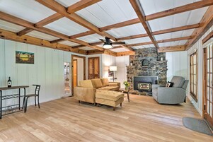 Una sala de estar acogedora con chimenea de piedra, vigas de madera y un sofá seccional.