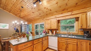 Cocina de cabaña de madera con una isla grande, armarios de madera, lavavajillas y cafetera.