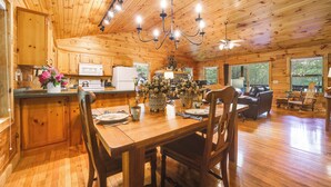 Interior de una cabaña de madera con comedor, cocina y zona de estar.