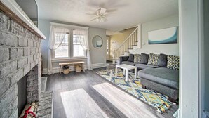 Een woonkamer met een open haard, een bank, een salontafel en een trap die naar een hoger niveau leidt.