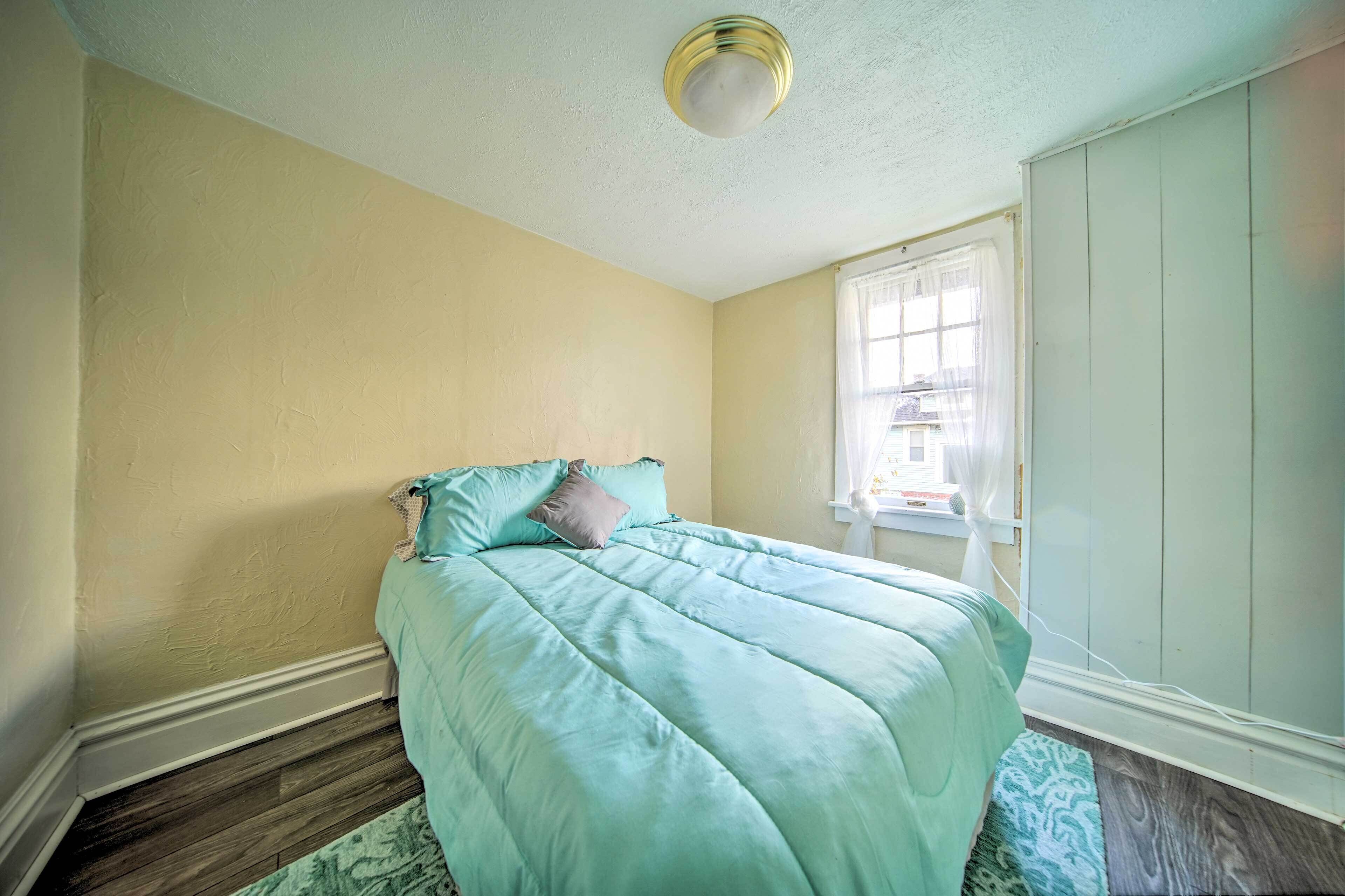 A bedroom with a bed, a window, and a ceiling light.