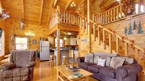 Ein Holzhäuschen im Inneren mit Wohnzimmer, Essbereich, Küche und einer Treppe.
