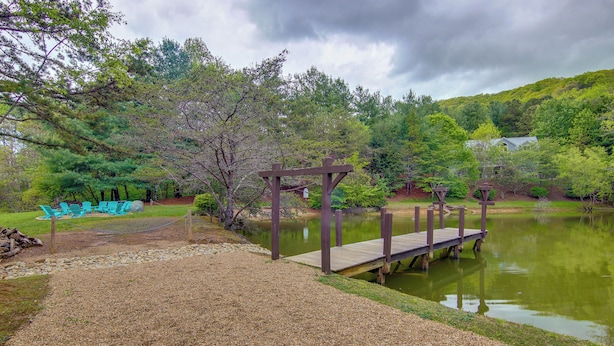 A wooden deck over a pond, surrounded by trees and a grassy area with chairs. - Modern Fairview Retreat: Spacious Deck + Mtn View! (Fairview)