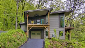 A two-story house with a covered porch, a garage, and a pathway leading to the entrance. - Modern Fairview Retreat: Spacious Deck + Mtn View! (Fairview)