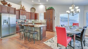 A modern kitchen with a central island, bar stools, and a dining area with a chandelier. - Fenced Hot Tub & Bbq: Modern Scottsdale Retreat (Scottsdale)
