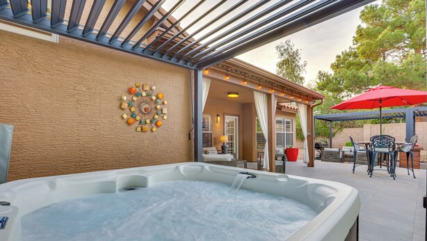 A hot tub with a pergola overhead, a patio area with outdoor furniture, and a decorative wall piece. - Fenced Hot Tub & Bbq: Modern Scottsdale Retreat (Scottsdale)