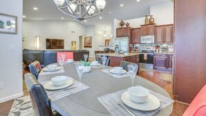 A modern kitchen with wooden cabinets, a stainless steel refrigerator, and a dining area with a round table set for six. - Fenced Hot Tub & Bbq: Modern Scottsdale Retreat (Scottsdale)