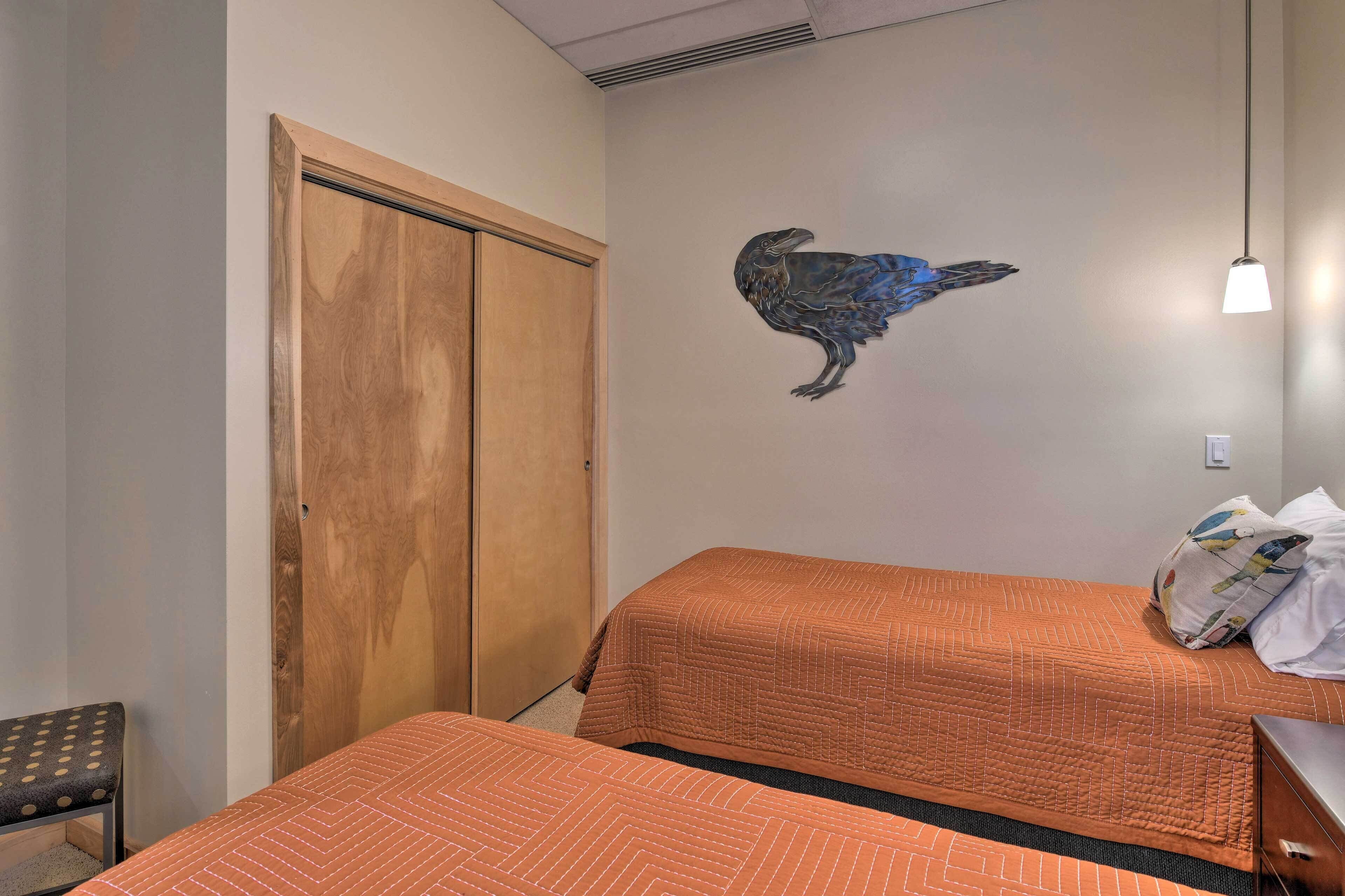 Ein Hotelzimmer mit zwei Betten, einem Holzschrank, einem Wandbild mit einem Vogel und einer Pendelleuchte.