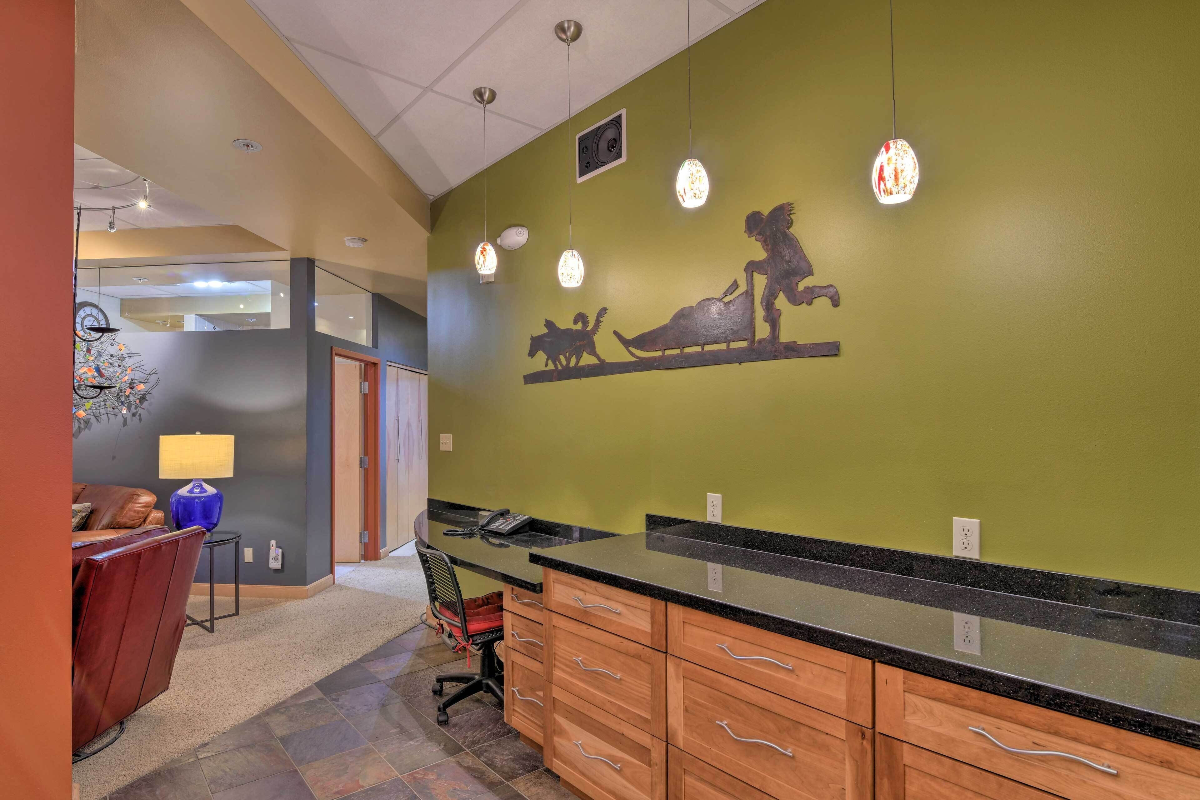 A kitchen with a black countertop, wooden cabinets, and a green wall with a mural.