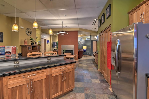 A kitchen with wooden cabinets, a stainless steel refrigerator, and pendant lighting. - Idyllic Dtwn Anchorage Condo w/ Fireplace! (Anchorage)