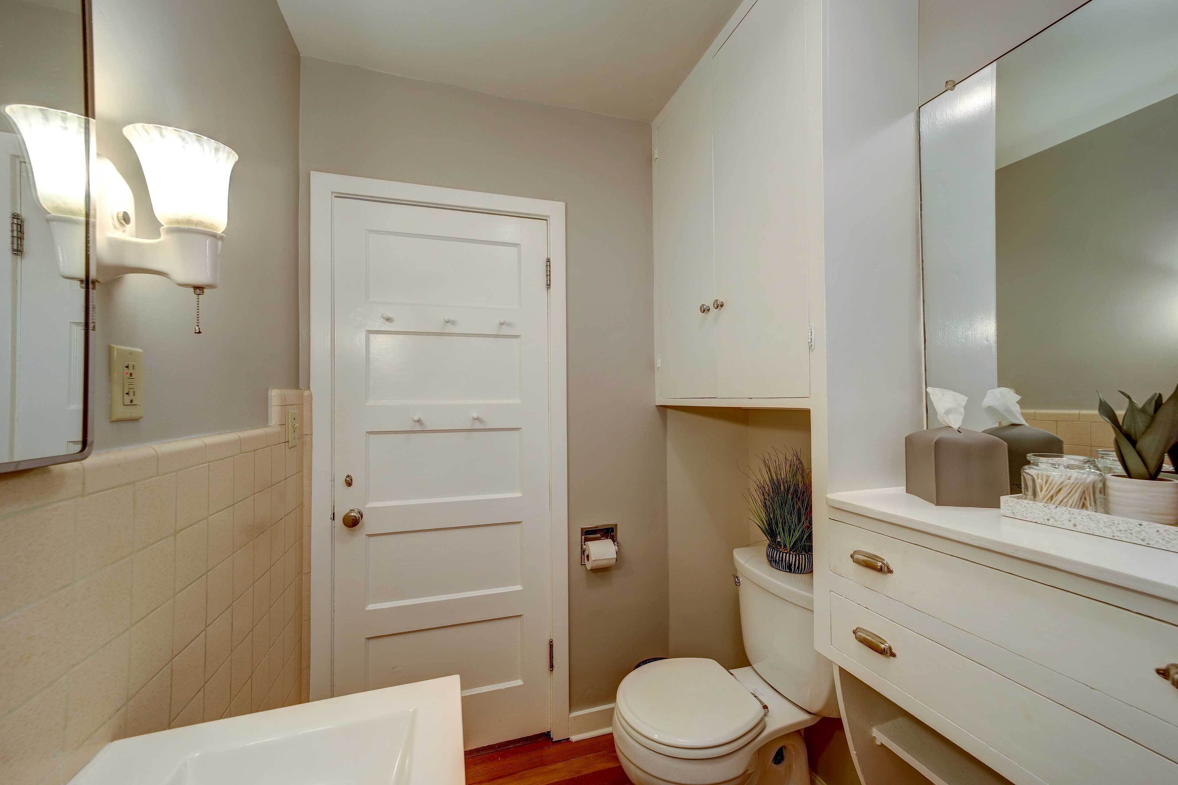 Een badkamer met toilet, wastafel, spiegel en kast.