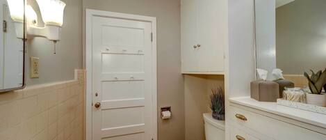 Een badkamer met toilet, wastafel, spiegel en kast.